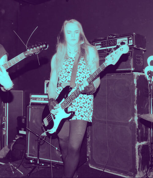 Biff playing bass in front of amplifier.