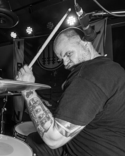 Jensen looking over right shoulder while playing drums