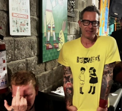 Tim standing in some venue wearing a Berzerk band shirt.