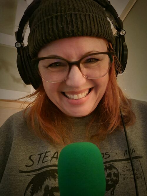 Tracy wearing headphones and speaking into a radio microphone.